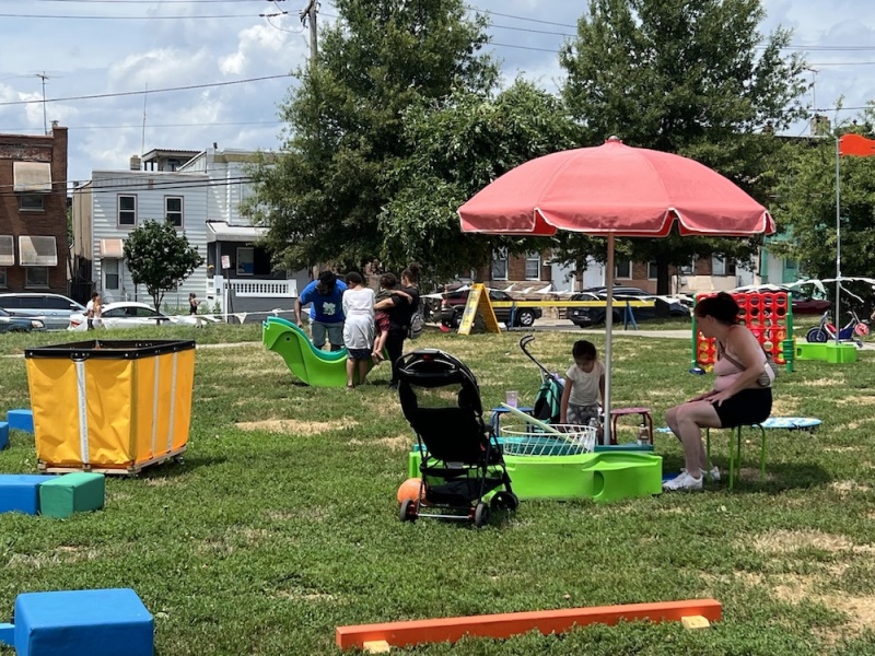 Children and families play in a park that has many games and toys available.