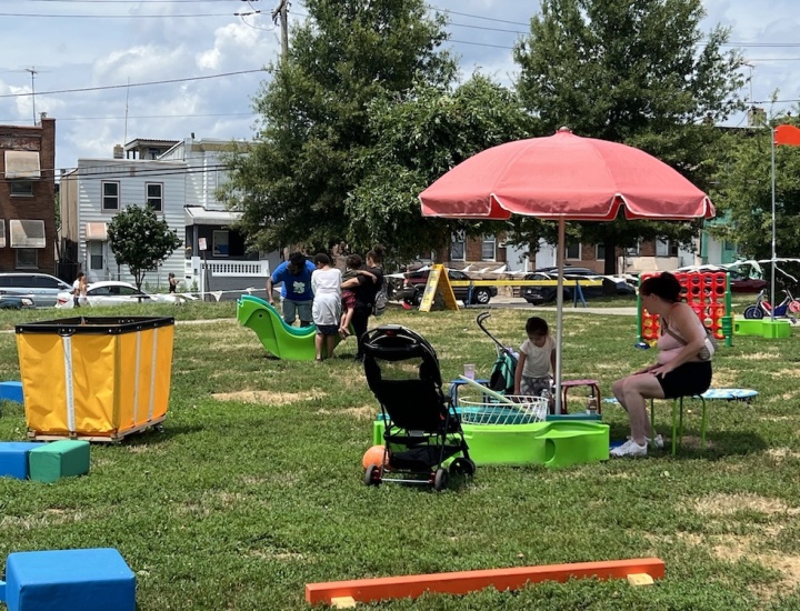 Children and families play in a park that has many games and toys available.