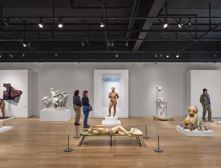 The Clay Studio's open showcase space with large sculptures and three people viewing the art.