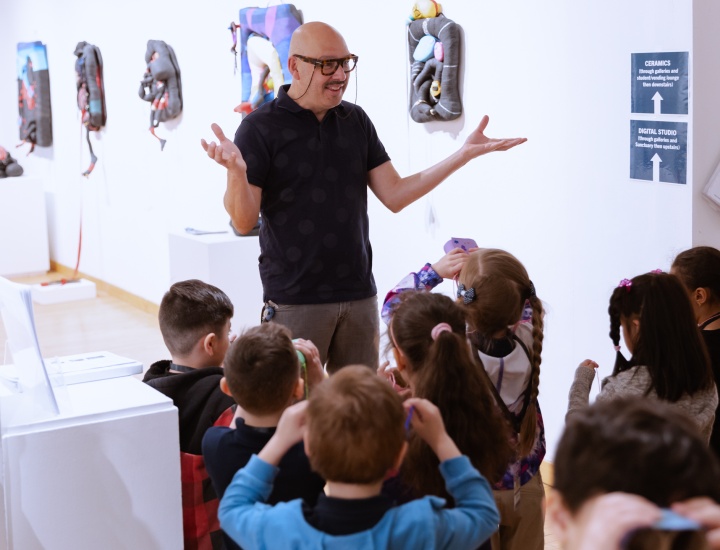 Male arts educator speaking with kindergarteners in gallery space